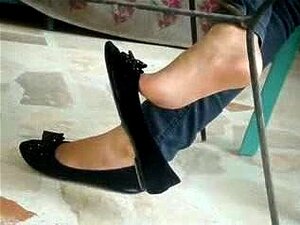 Pies sexys colgando con un zapato plano negro
